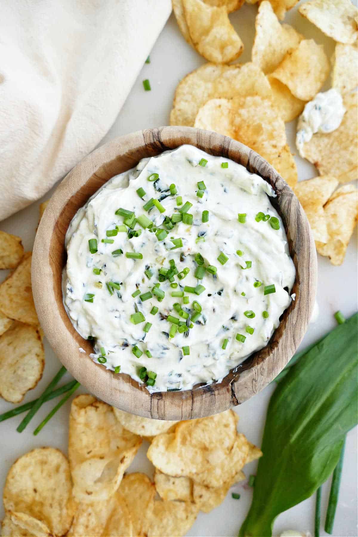 creamy ramp dip in a bowl topped with chives and surrounded by chips