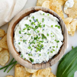 creamy ramp dip in a bowl topped with chives and surrounded by chips