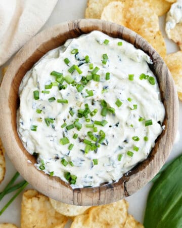 creamy ramp dip in a bowl topped with chives and surrounded by chips