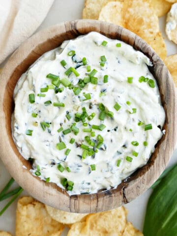 creamy ramp dip in a bowl topped with chives and surrounded by chips