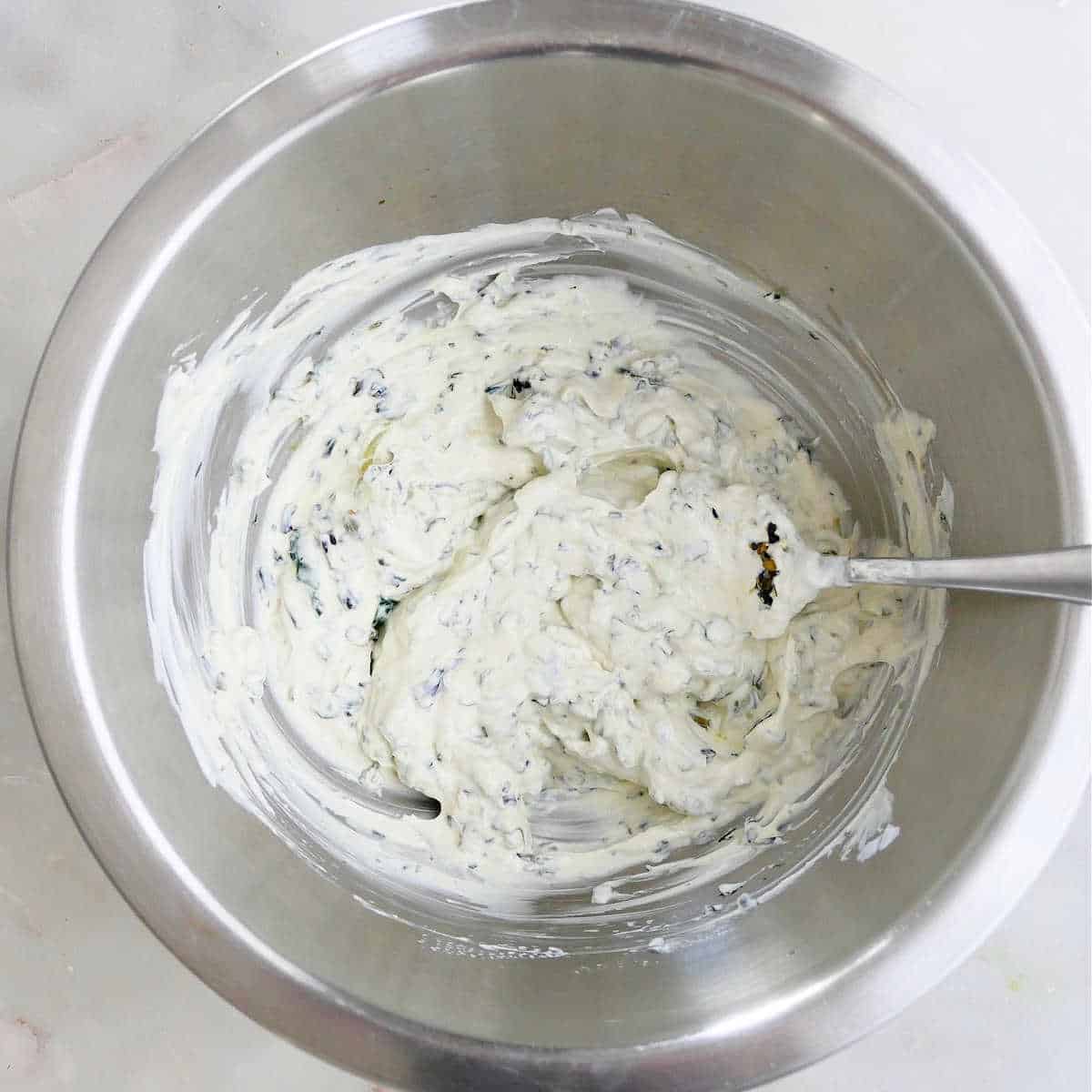 cooked ramps being mixed with yogurt and other ingredients in a bowl