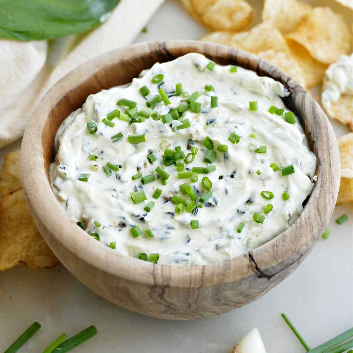 creamy ramp dip in a bowl topped with slices chives on a counter