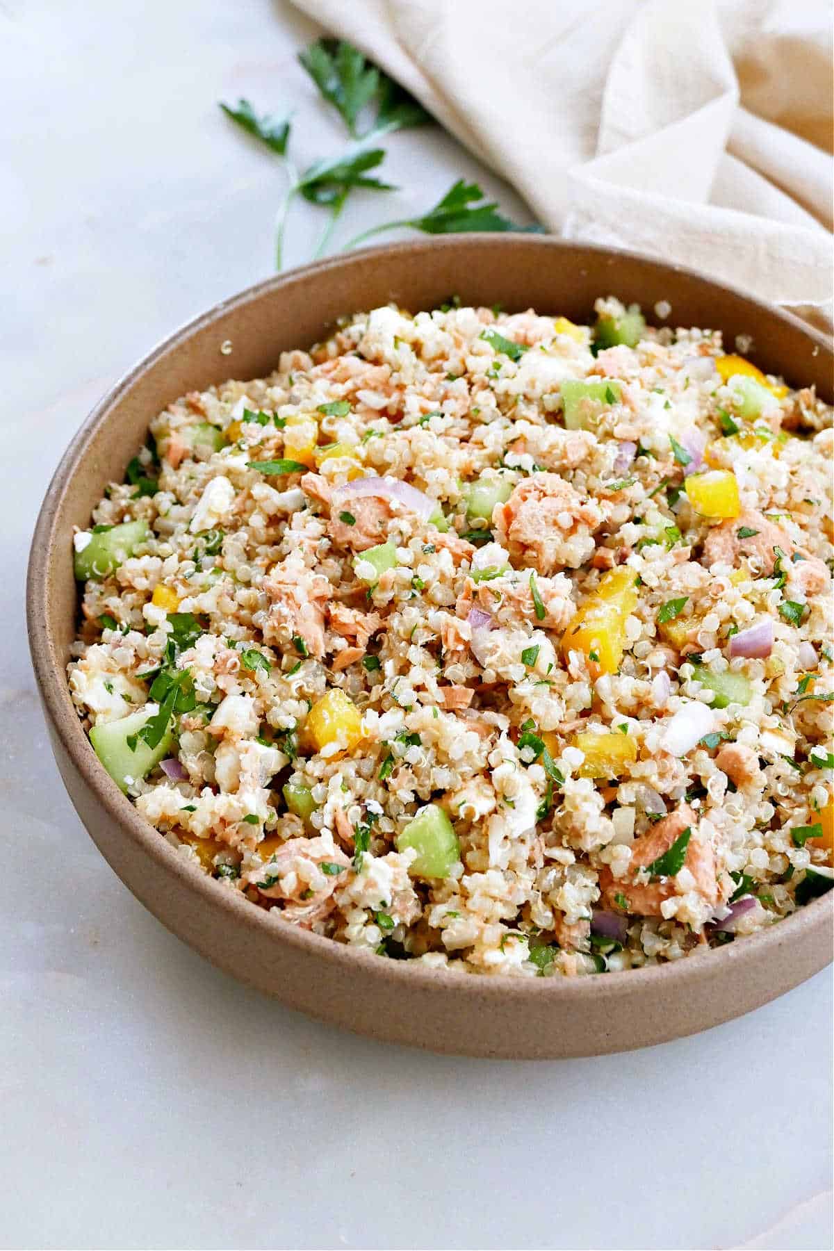 quinoa salad with canned salmon, vegetables, and feta cheese in a serving bowl