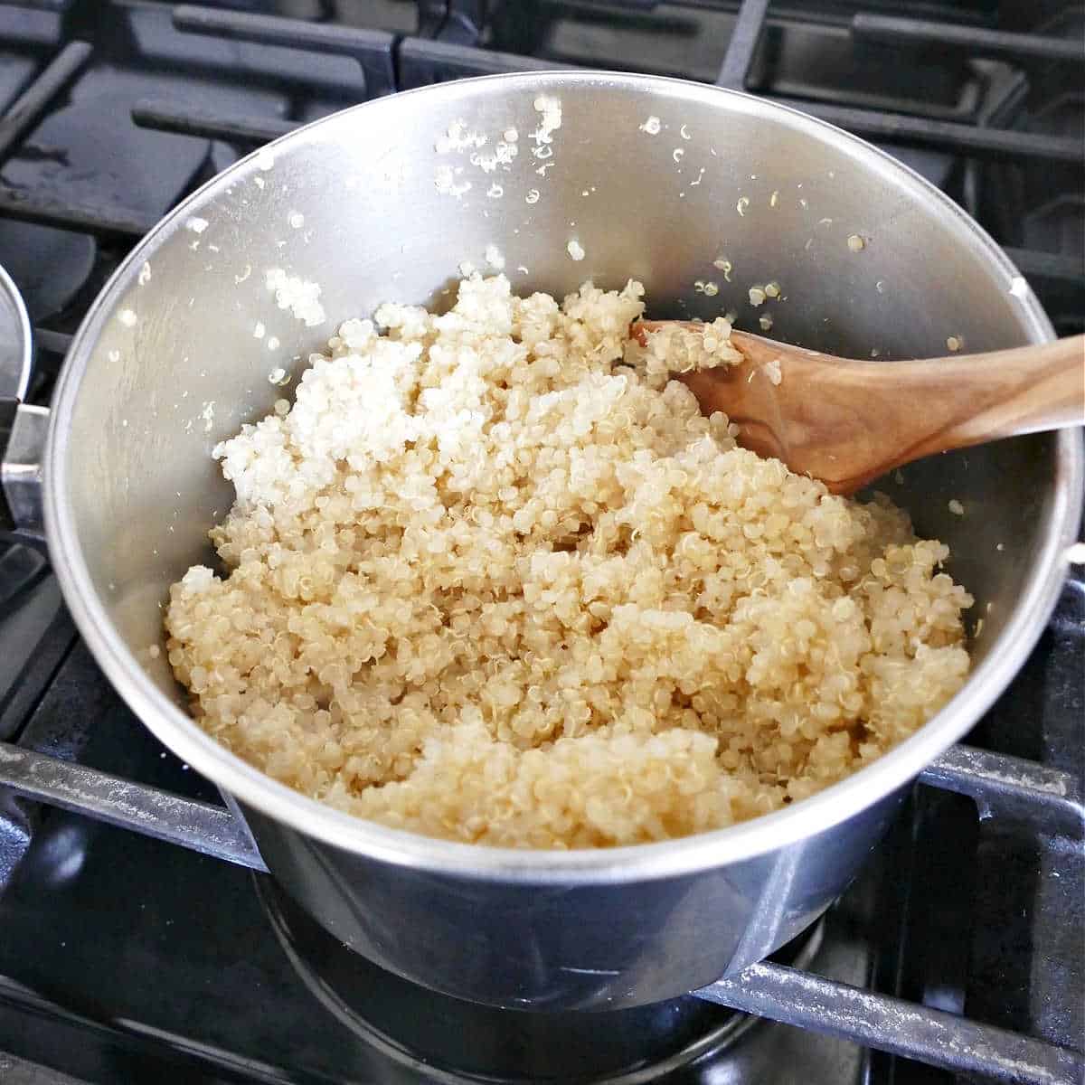 quinoa cooked in a saucepan with a wooden spoon on a stovetop