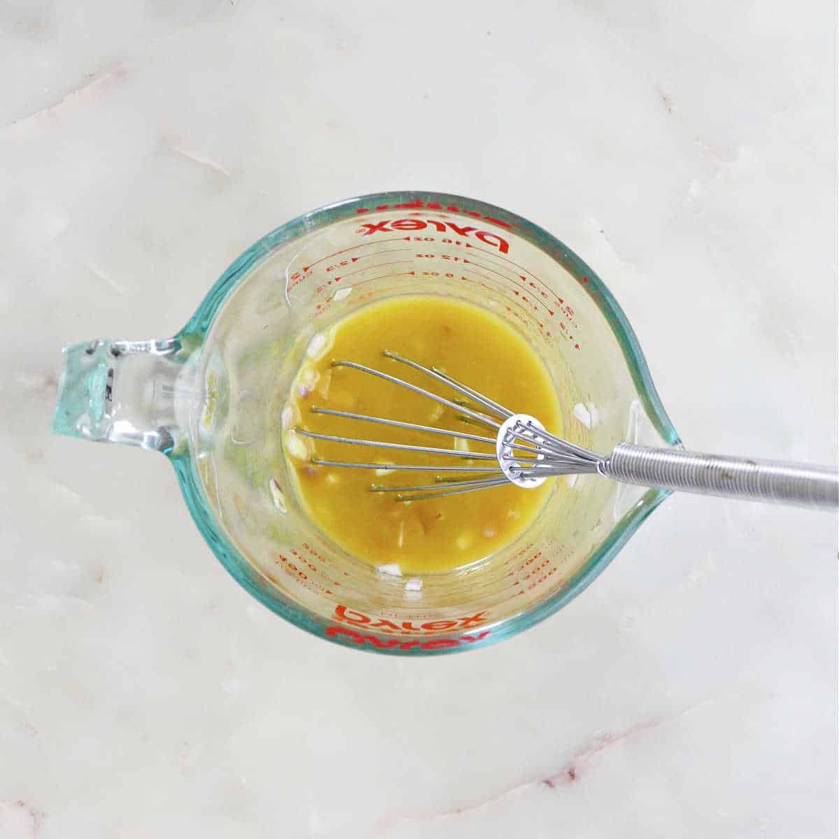 lemon dressing for salmon quinoa salad whisked together in a measuring cup on a counter
