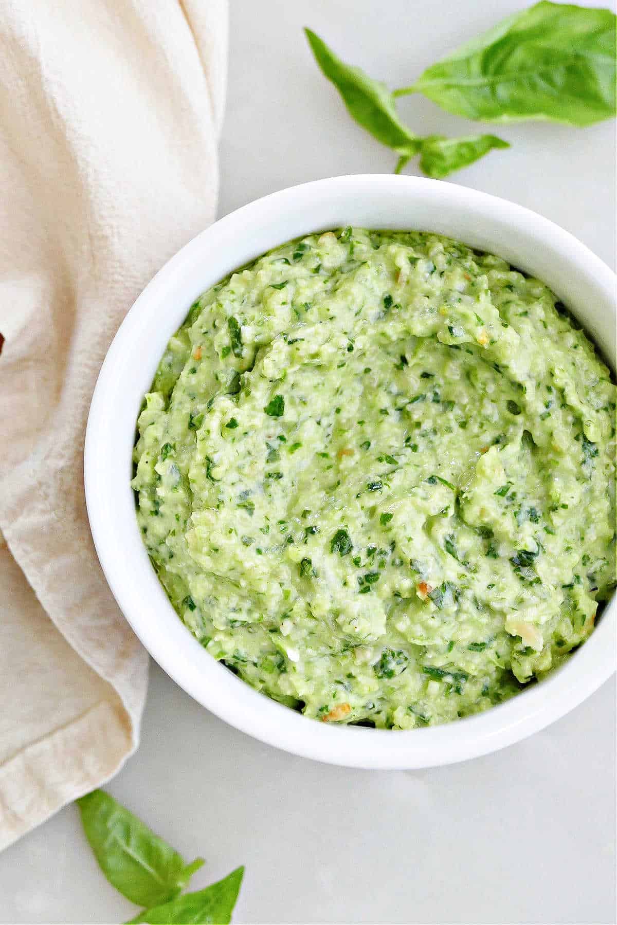 green onion and basil pesto made with pine nuts in a serving bowl on a counter