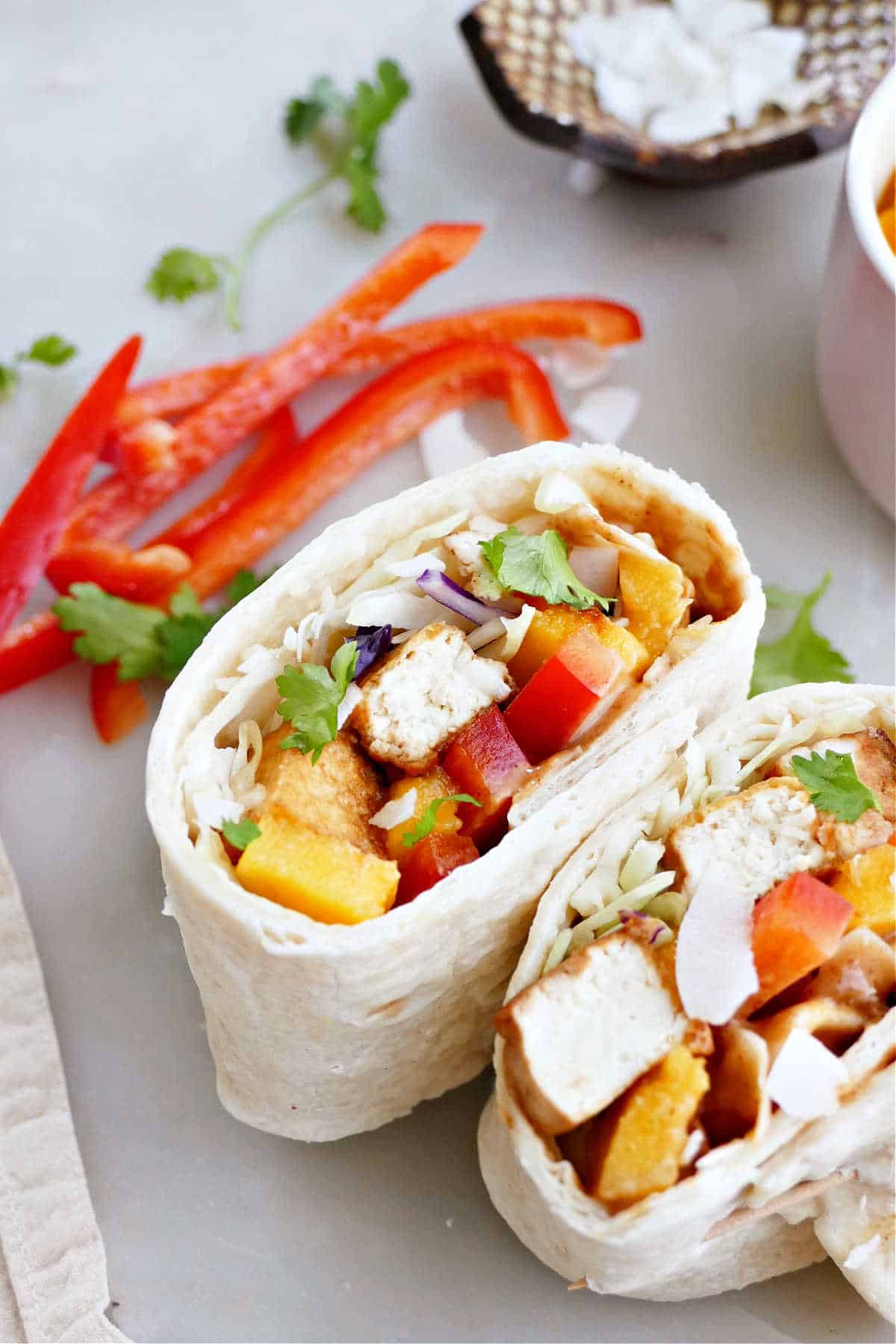 tofu wrap with bell pepper, mango, and peanut sauce on a counter
