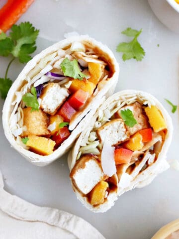 tofu wrap sliced in half on a counter surrounded by ingredients