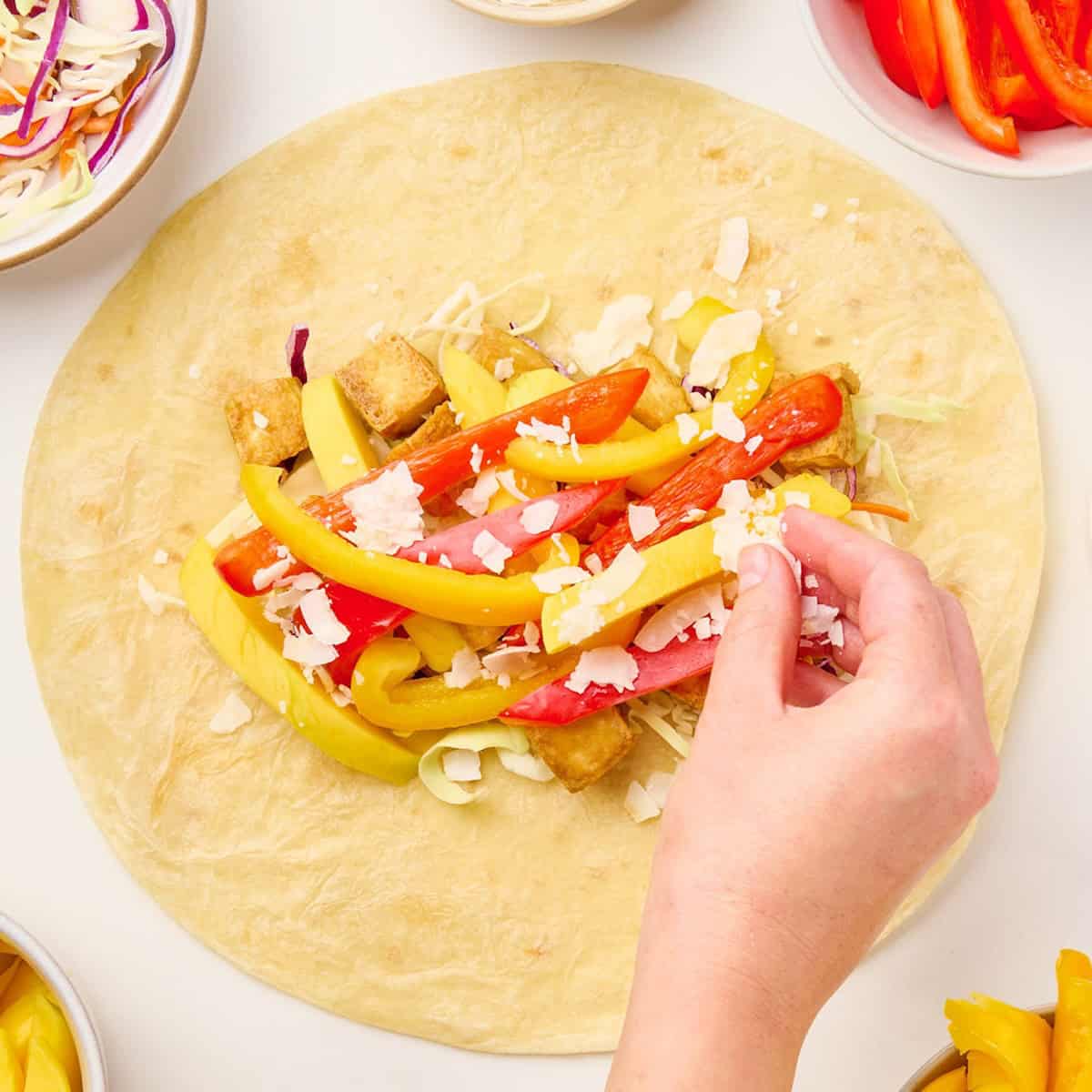 Woman adding coconut to other ingredients for tofu wraps in a tortilla.