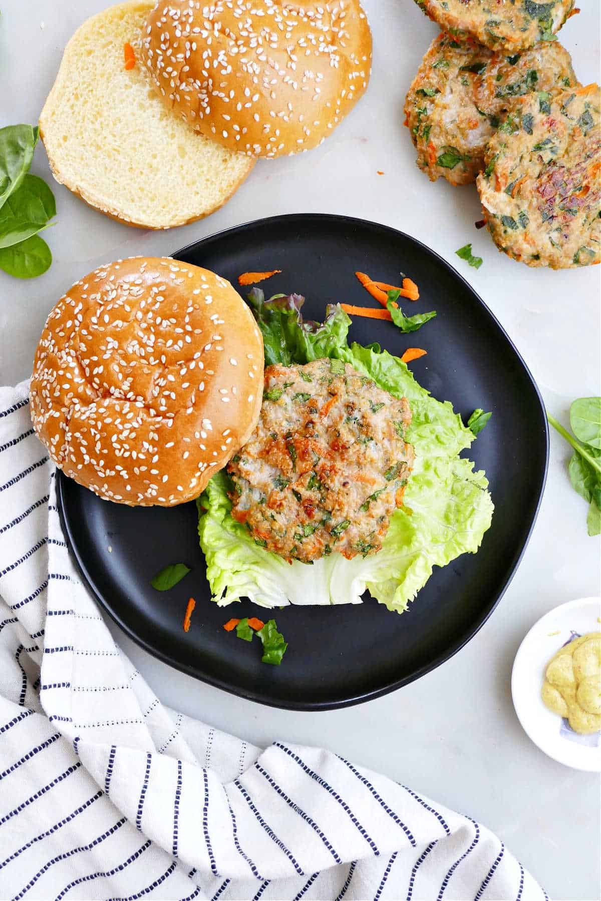 veggie chicken burger on a bun with lettuce on a plate surrounded by ingredients