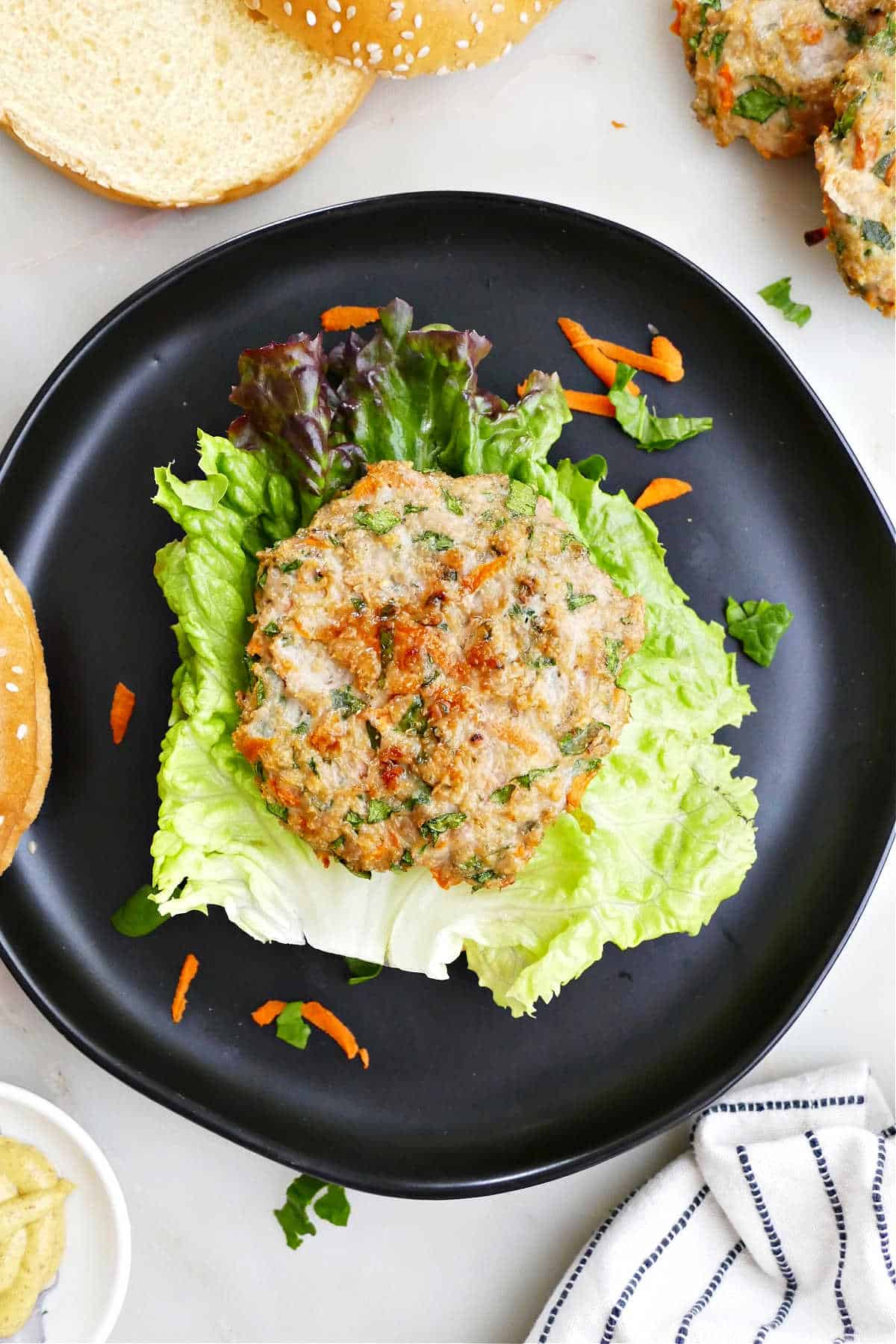 vegetable chicken patty on top of a piece of lettuce on a bun on a plate