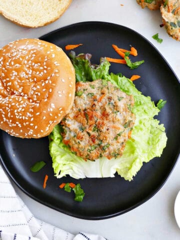 veggie chicken burger on a bun with lettuce on a plate surrounded by ingredients