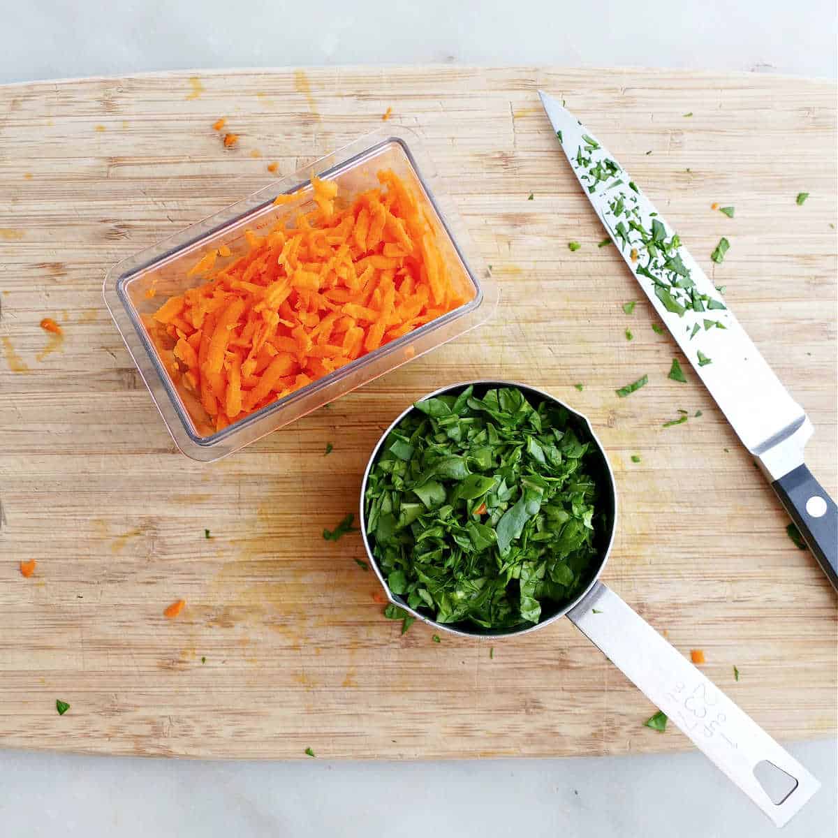 shredded carrots and chopped spinach in measuring cups on a cutting board