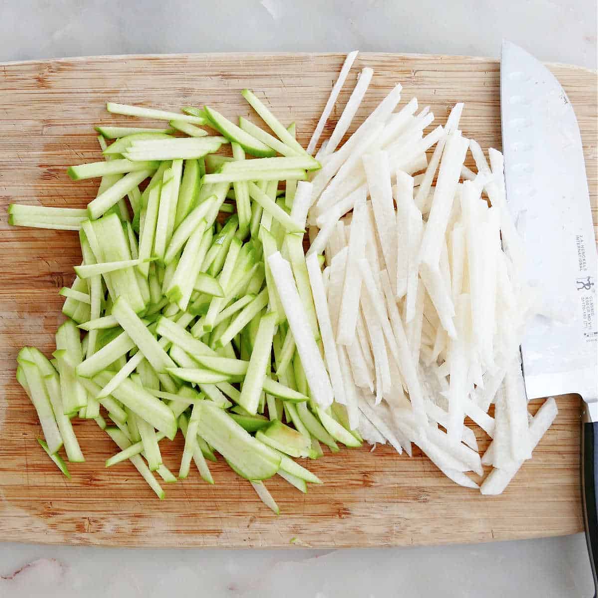 green apples and jicama cut into matchsticks on a cutting board next to a knife