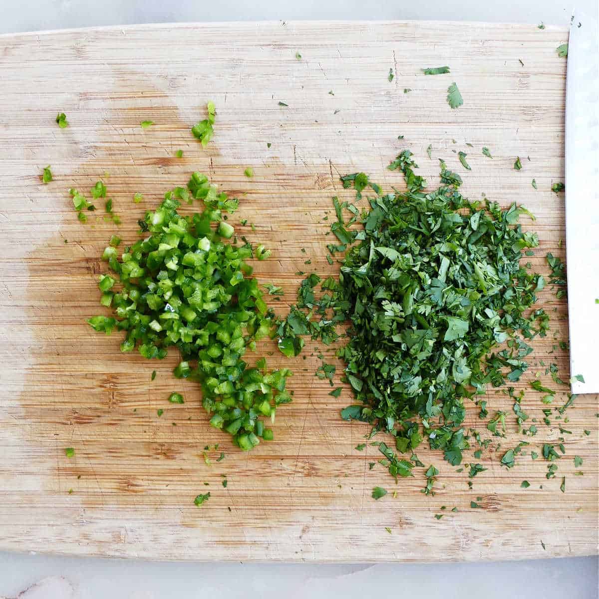 diced jalapeño and cilantro on a cutting board next to a knife