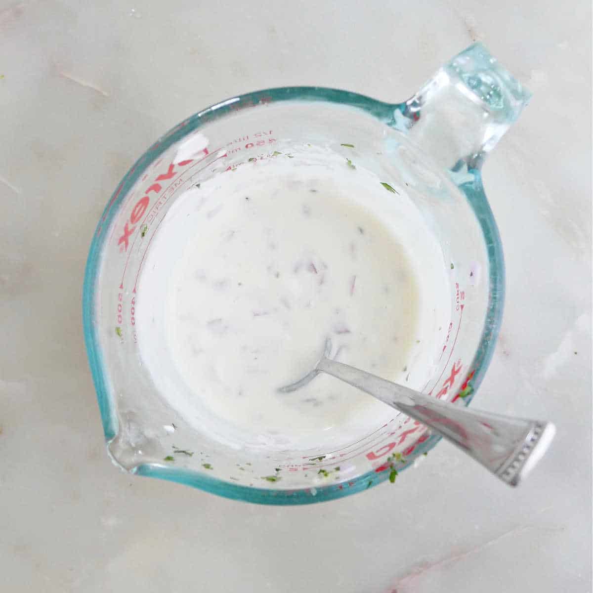 yogurt lime dressing mixed together in a measuring cup with a spoon