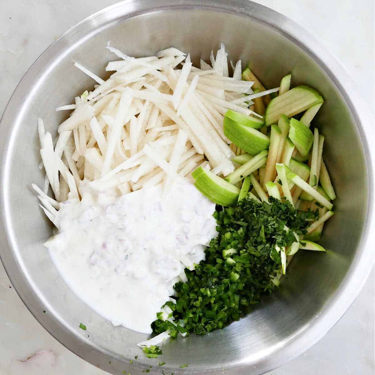 ingredients for apple jicama slaw in a mixing bowl before being stirred
