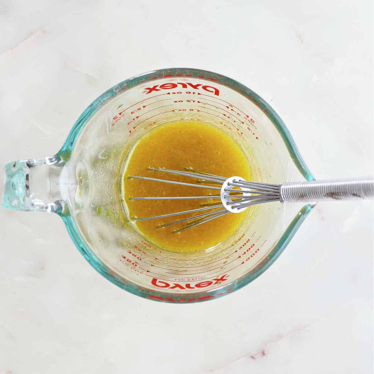 olive oil, honey, Dijon, and apple cider vinegar whisked together in a measuring cup.