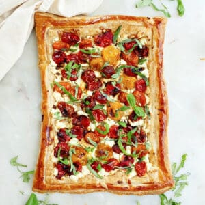 roasted cherry tomato tart on a counter next to basil leaves and a napkin