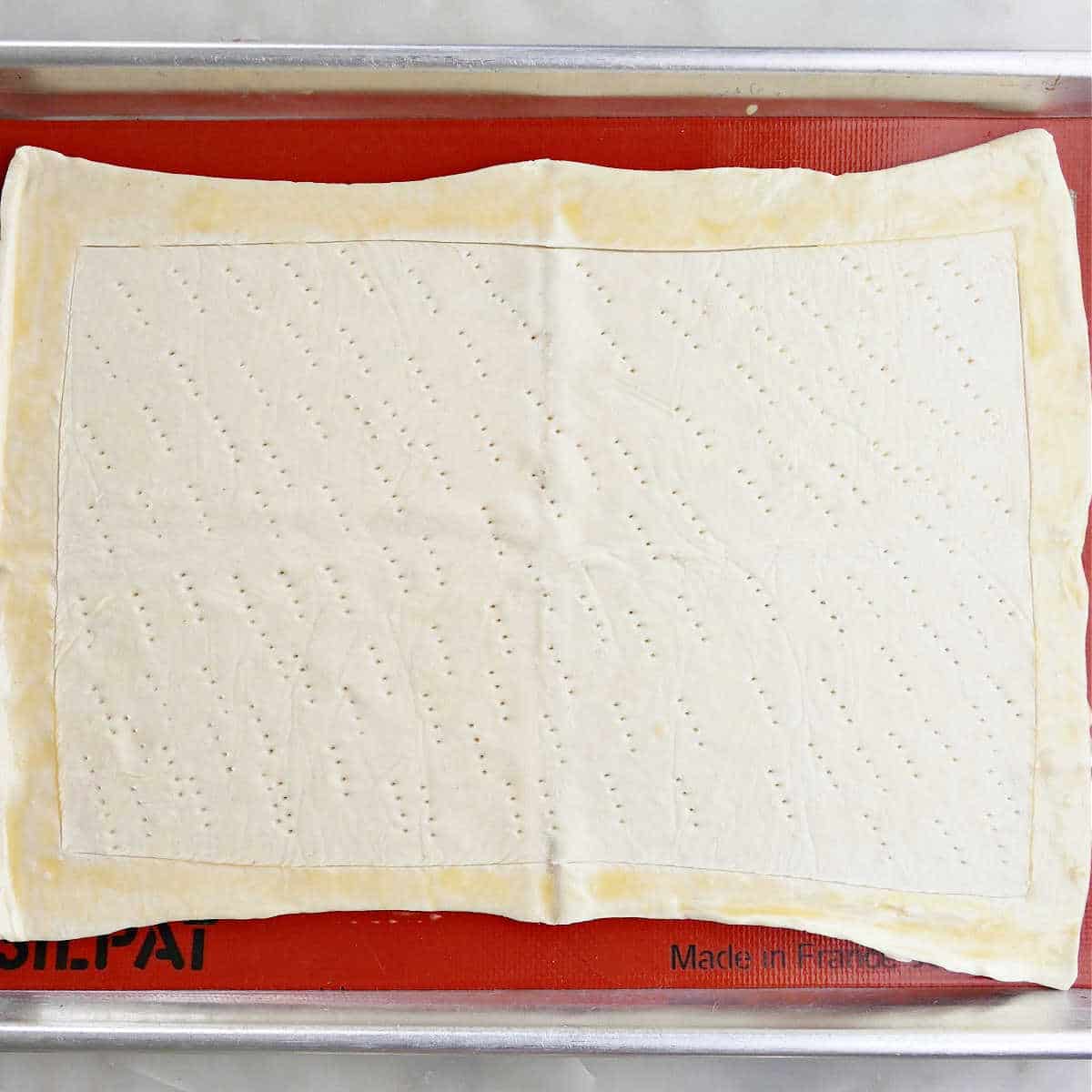 puff pastry on a lined baking sheet with egg wash brushed on edges