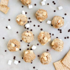 s'mores balls on a counter surrounded by mini marshmallows and chocolate chips