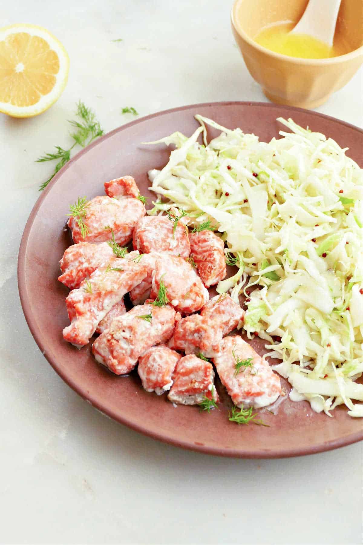 lemon butter salmon bites and coleslaw on a plate next to ingredients