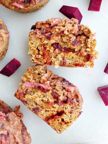a beet muffin sliced in half on a counter next to other muffins