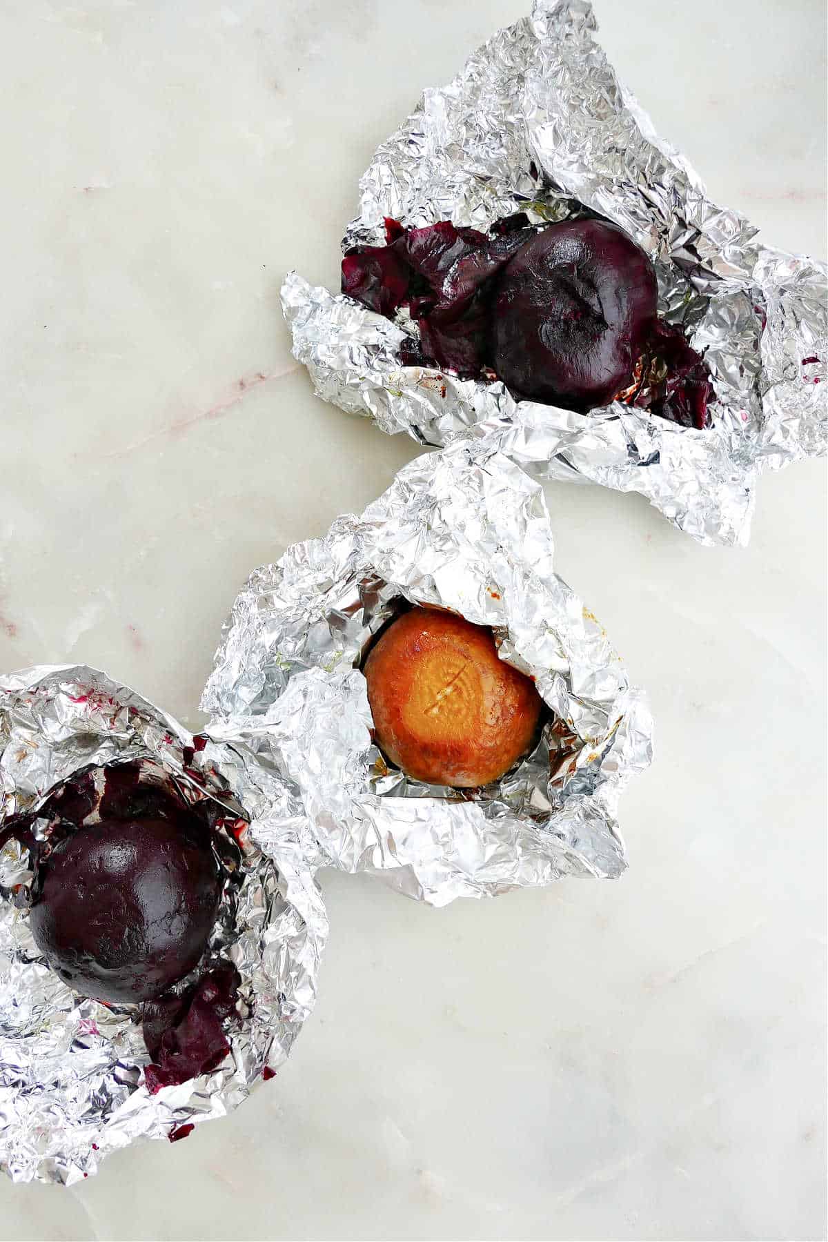 roasted beets in foil packets next to each other on a counter
