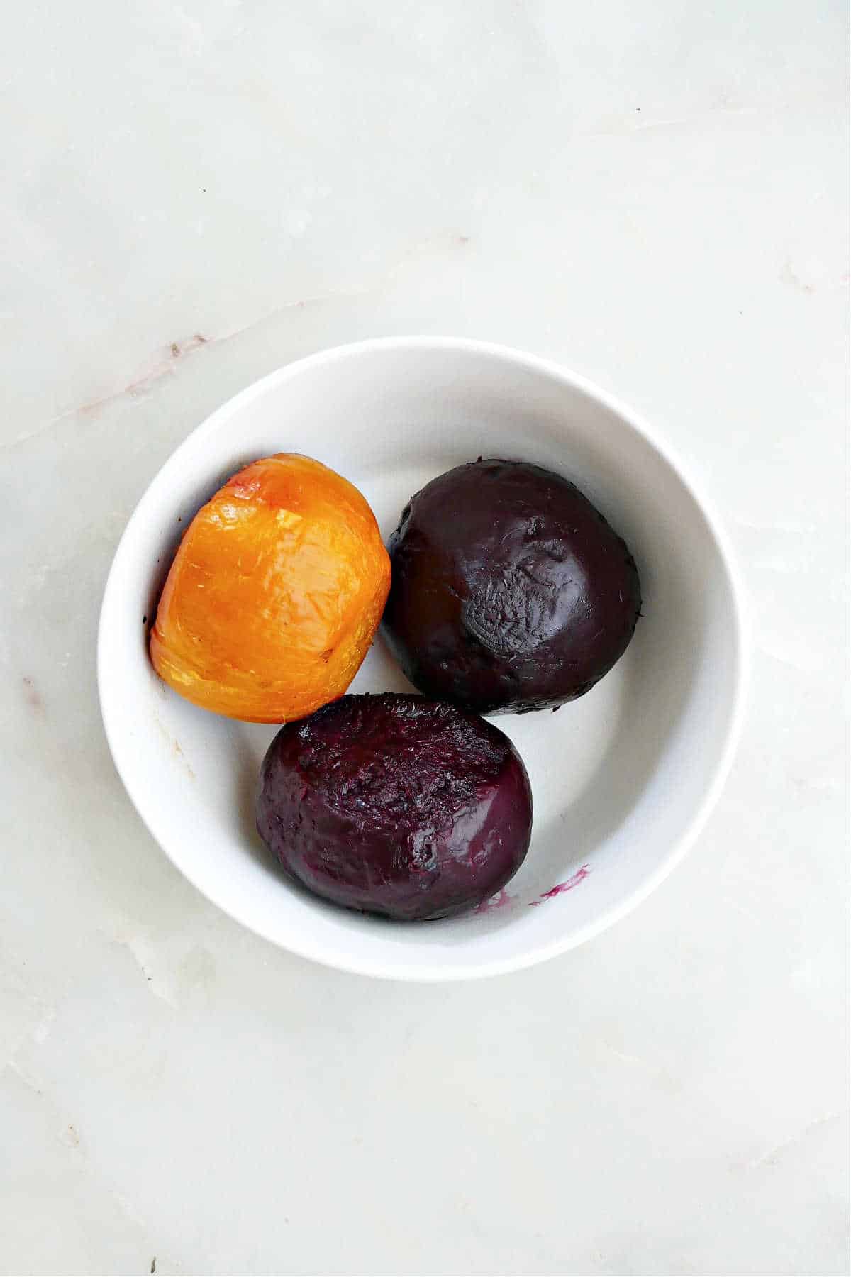 2 roasted red beets and 1 roasted golden beet in a bowl on a counter