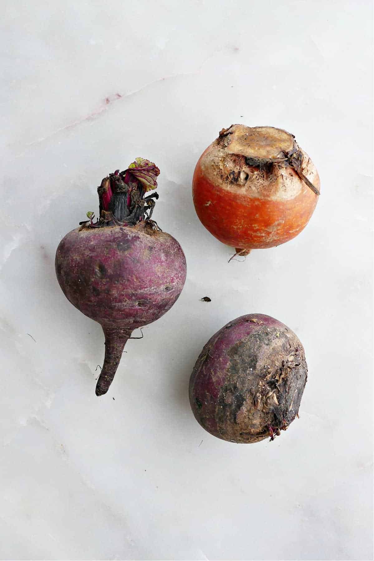 2 red beets and 1 golden beet next to each other on a counter