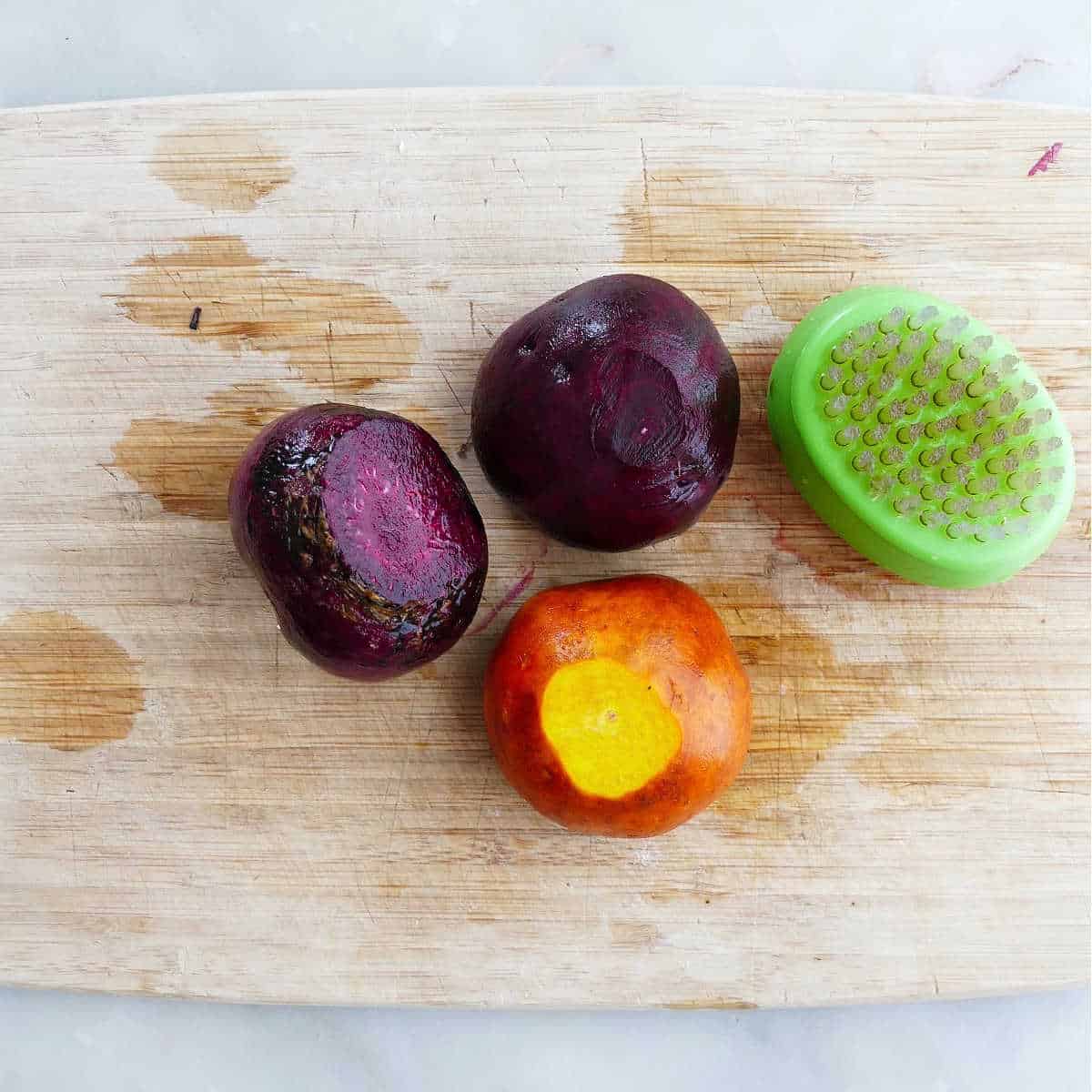 beets being scrubbed with a vegetable brush on a cutting board
