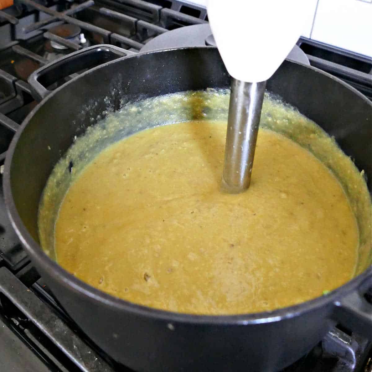 immersion blender in a soup pot blending a soup