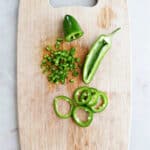 jalapeños cut into different ways on a cutting board