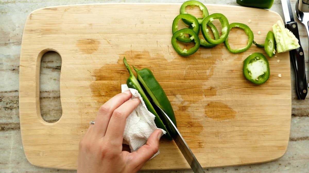 woman slicing a jalapeño pepper in half lengthwise for poppers