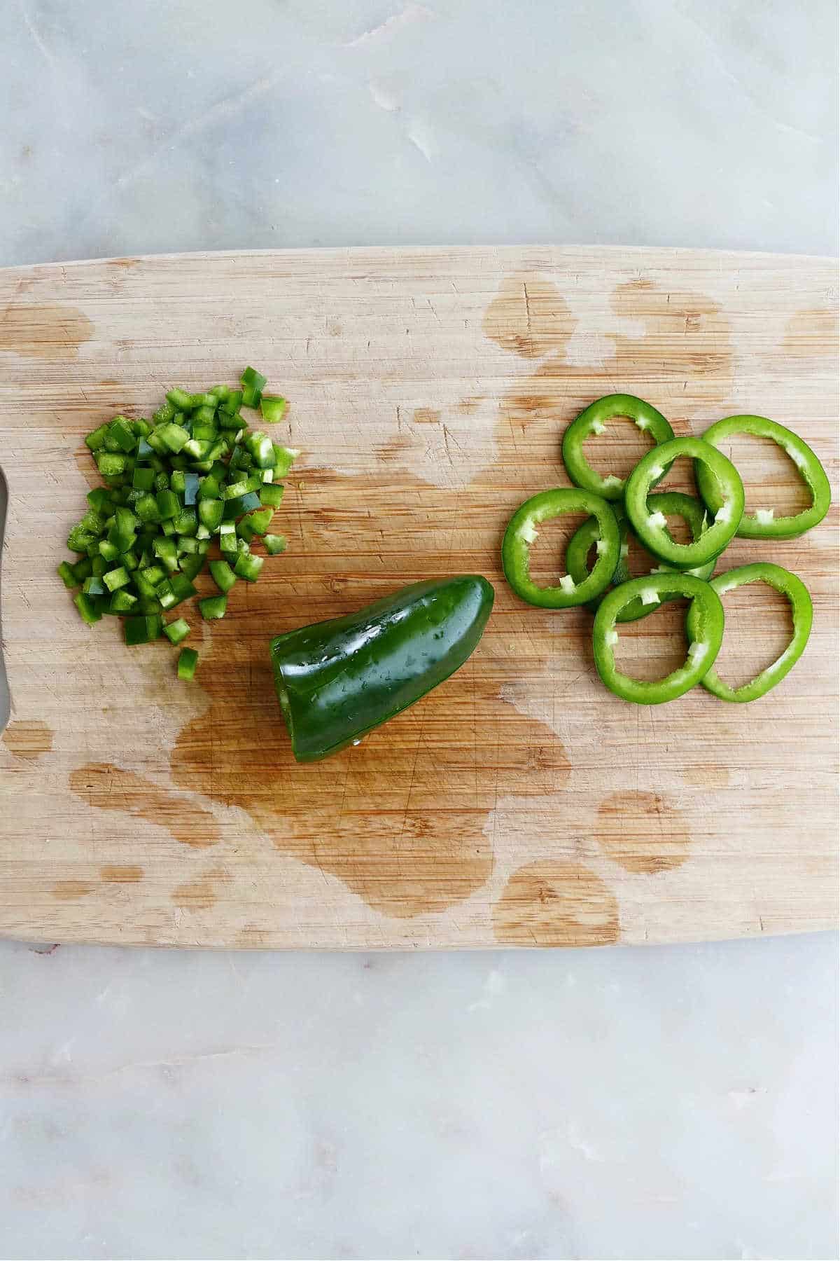 diced, whole, and sliced jalapeños next to each other on a cutting board