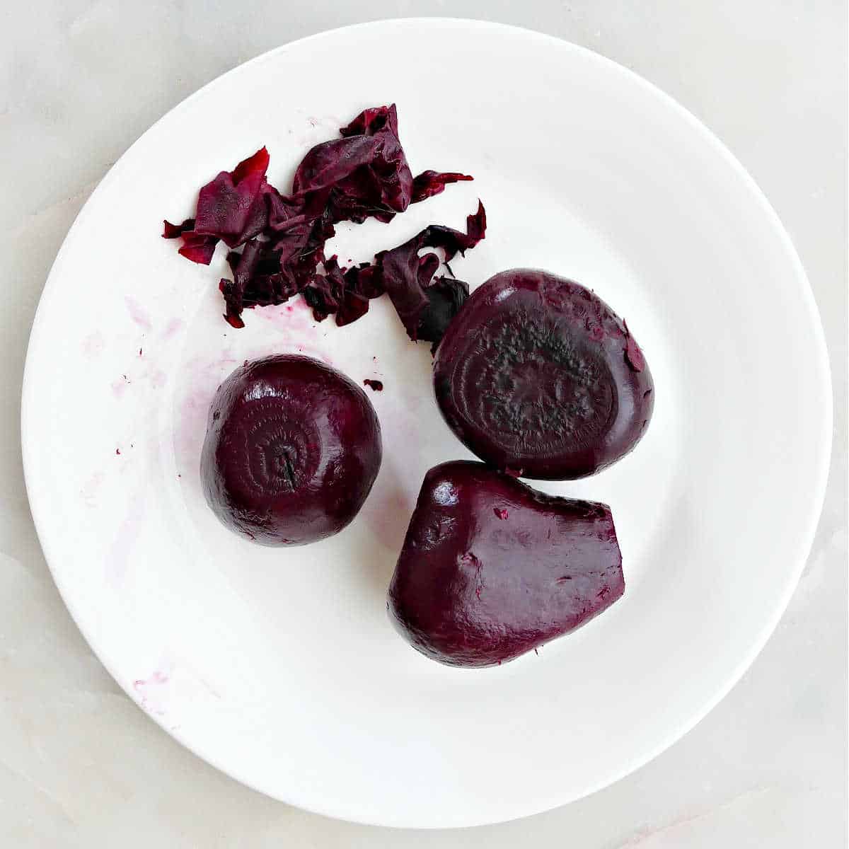 cooked beets with the skin peeled off in a bowl on a counter