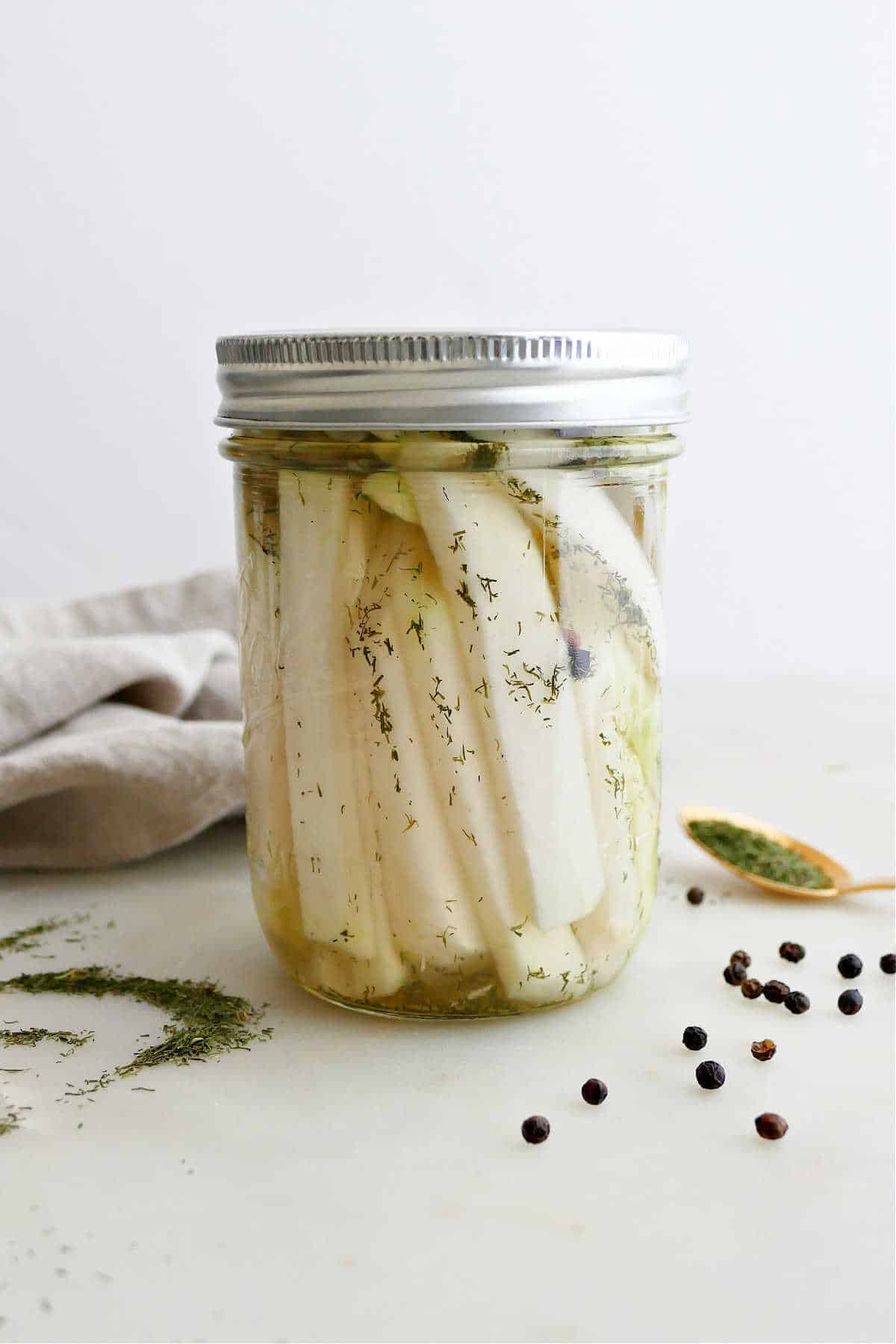 pickled kohlrabi spears in a wide mouth glass jar with lid on a counter