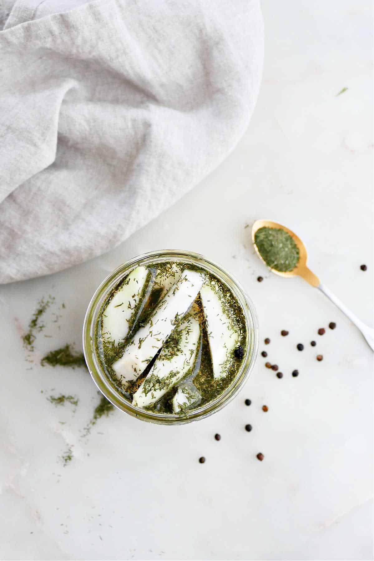 overhead view of pickled kohlrabi spears with dill in a glass jar