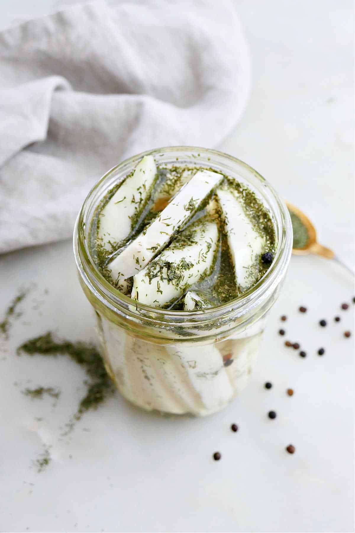 overhead view of pickled kohlrabi spears with dill in a glass jar