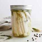 pickled kohlrabi spears in a wide mouth glass jar with lid on a counter