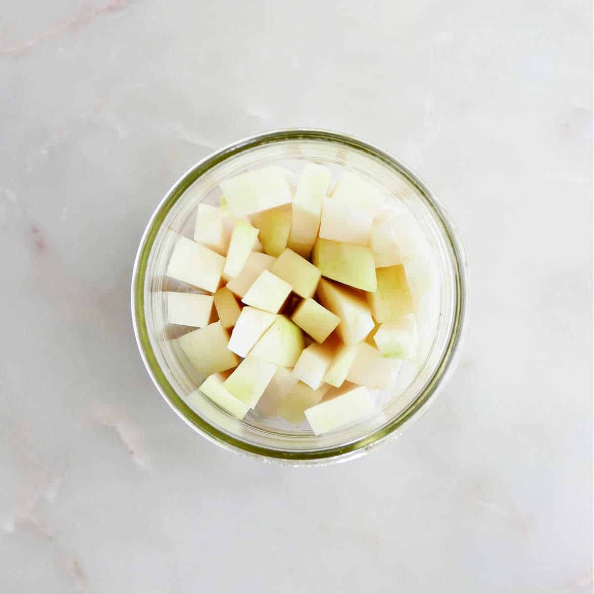 kohlrabi spears stuffed into a wide mouth glass jar on a counter