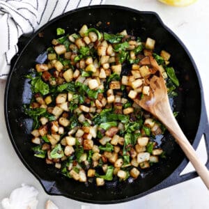 sautéed kohlrabi and greens in a cast iron skillet with a wooden spoon