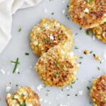 corn fritters on a counter sprinkled with feta and chives