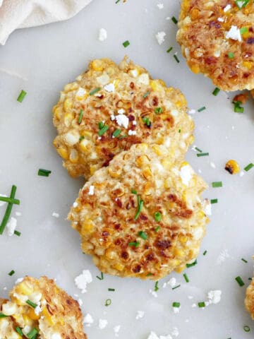 corn fritters on a counter sprinkled with feta and chives