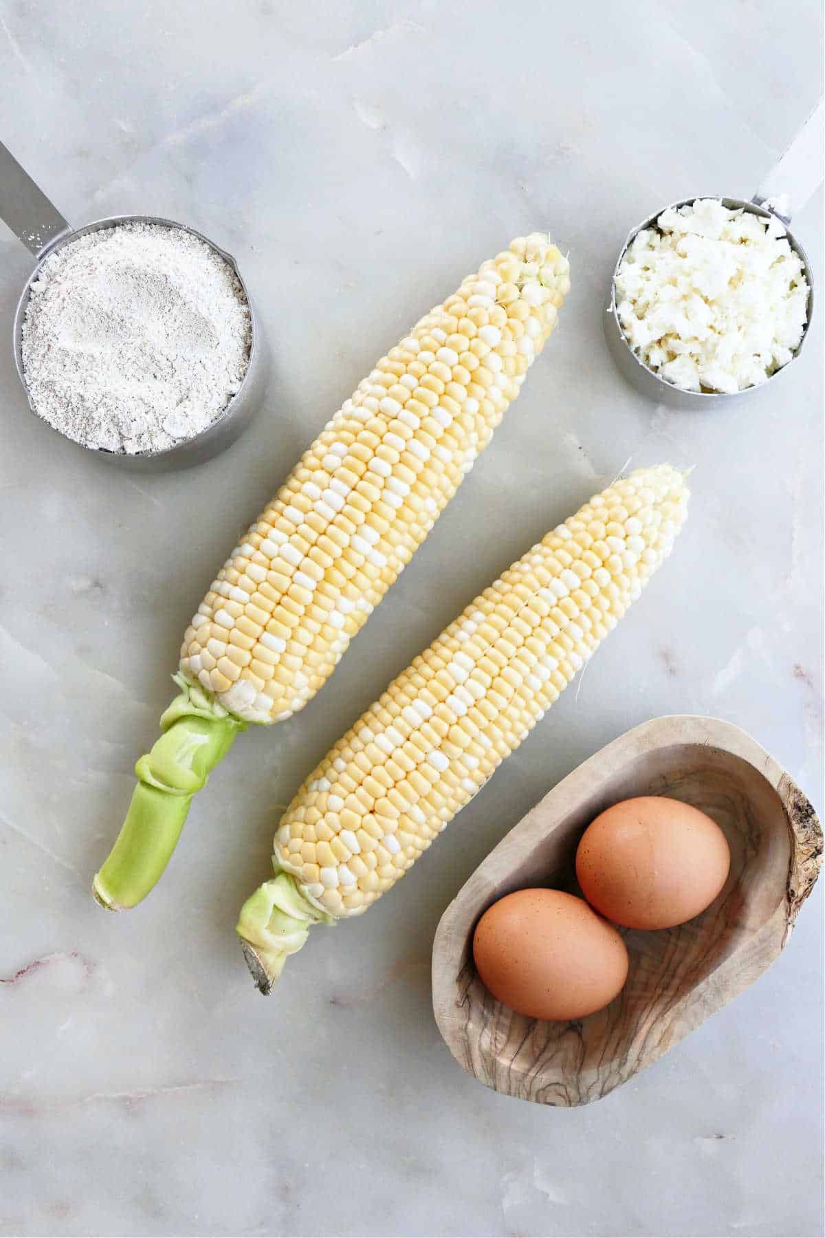 ground oats, corn on the cob, feta cheese, and eggs on a counter