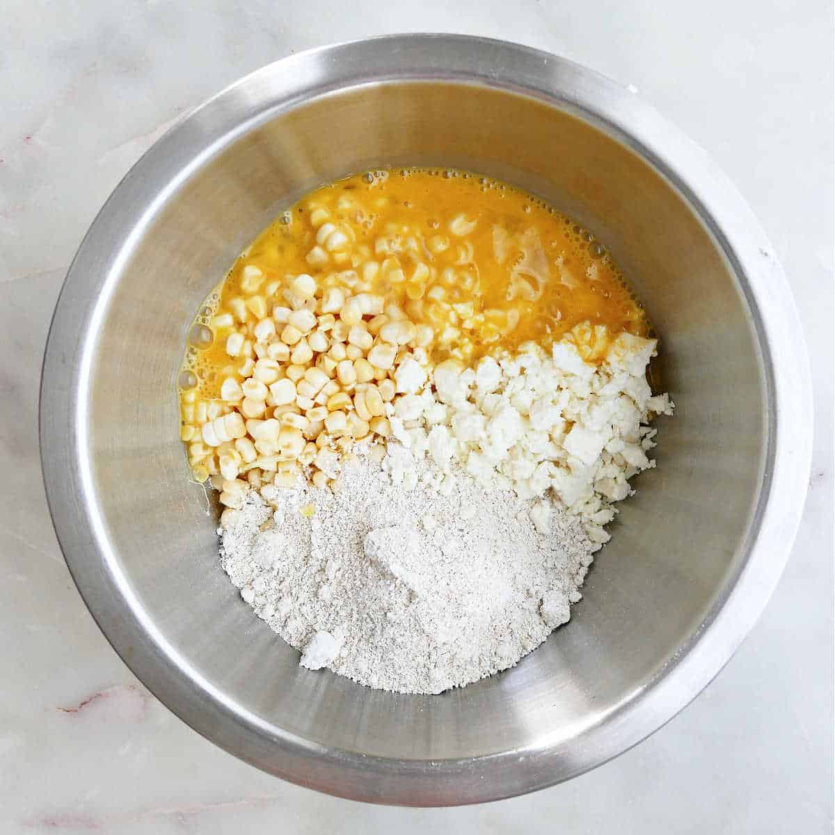 sweet corn, ground oats, feta cheese, and beaten eggs in a mixing bowl