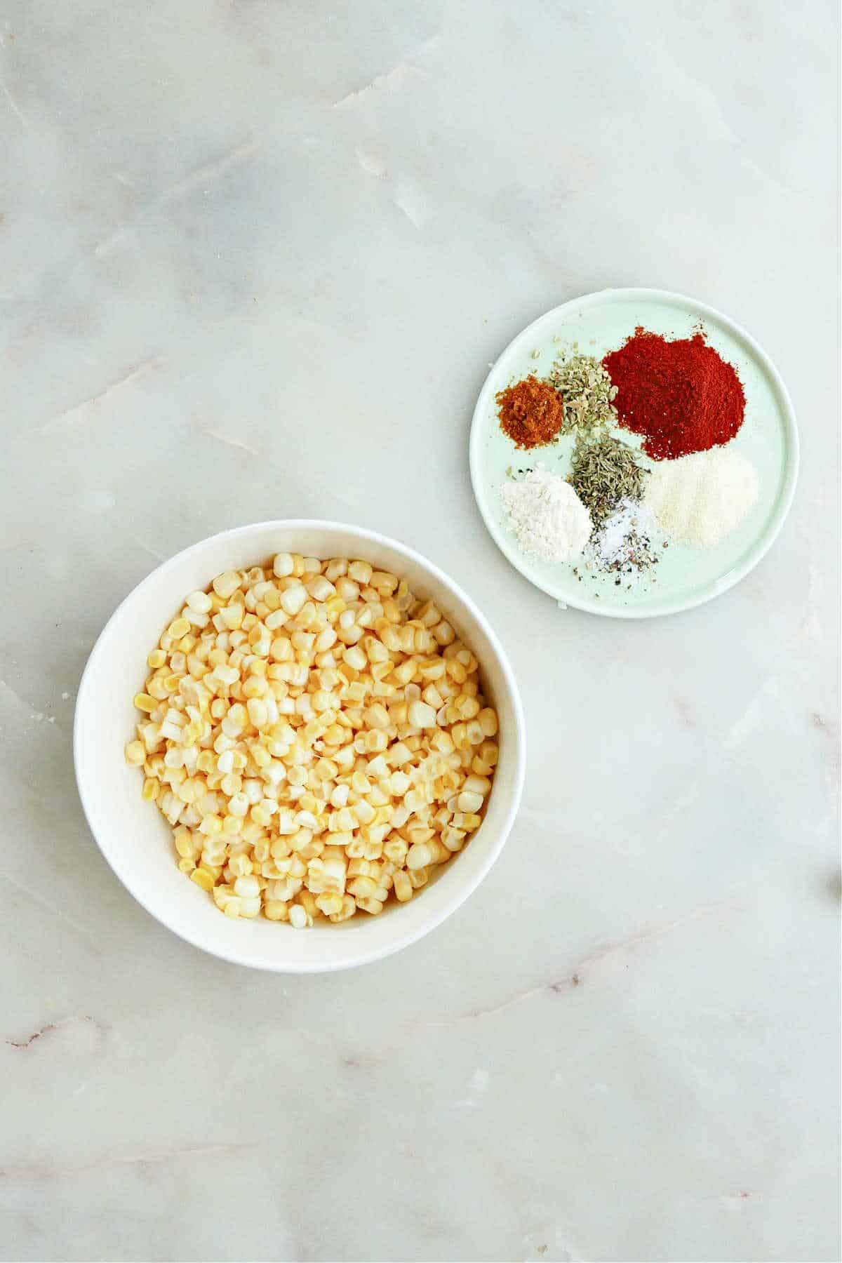 sweet corn in a bowl and spices on a plate next to each other