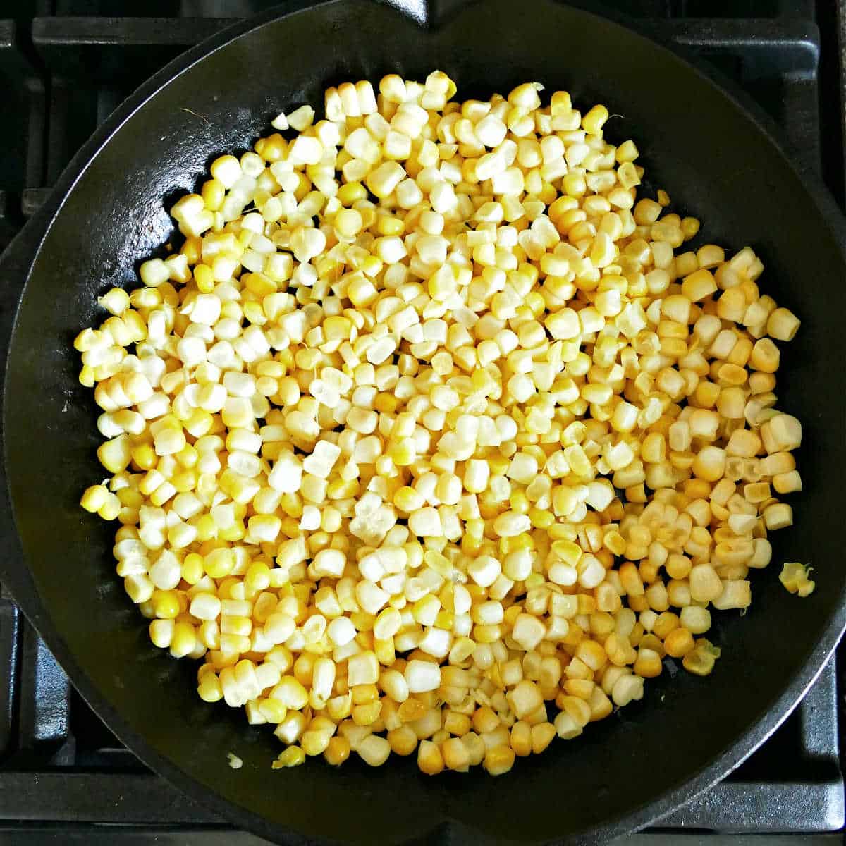 sweet corn cooking in olive oil in a skillet on a stovetop