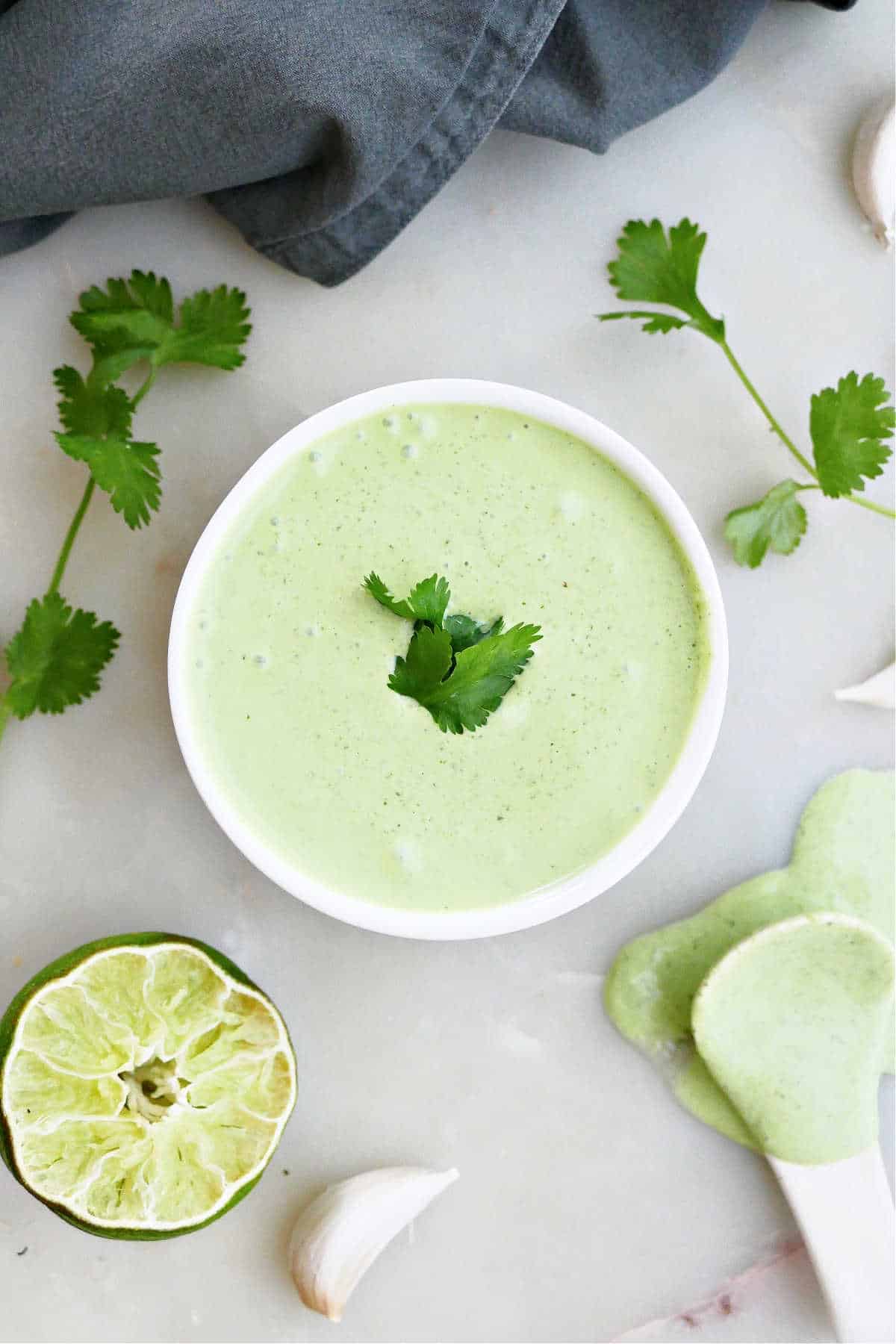 cilantro garlic sauce in a bowl surrounded by ingredients