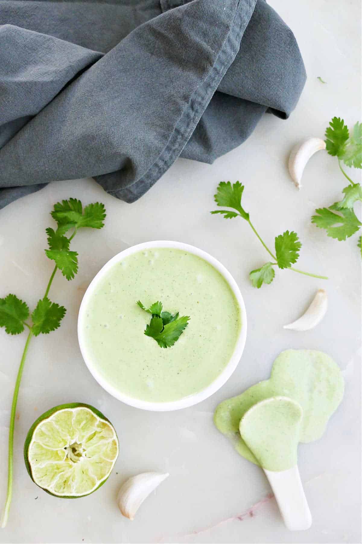 cilantro garlic yogurt sauce in a bowl next to ingredients on a counter